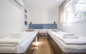 A small, clean room with two single beds, a window, and a wall-mounted air conditioner. - Stunning home in Zerava (Zerava)