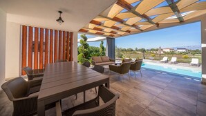 An outdoor patio with a dining table, chairs, and a view of a swimming pool. - Stunning home in Zerava (Zerava)