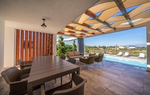 An outdoor patio with a dining table, chairs, and a view of a swimming pool. - Stunning home in Zerava (Zerava)