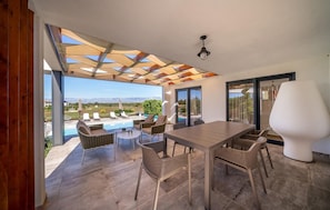 A covered outdoor seating area with a pool, lounge chairs, and a table. - Stunning home in Zerava (Zerava)