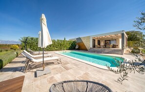 Ein moderner Poolbereich mit Liegestühlen und einer überdachten Sitzgelegenheit.
