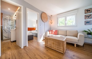 A modern living room with a sofa, a coffee table, and a window with natural light. - Beautiful home in Zerava (Zerava)
