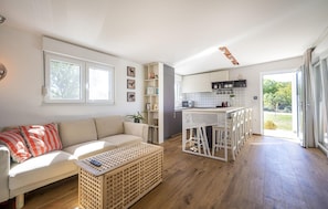 Una cocina moderna con armarios blancos, un comedor con sillas blancas y un amplio ventanal que proporciona luz natural.