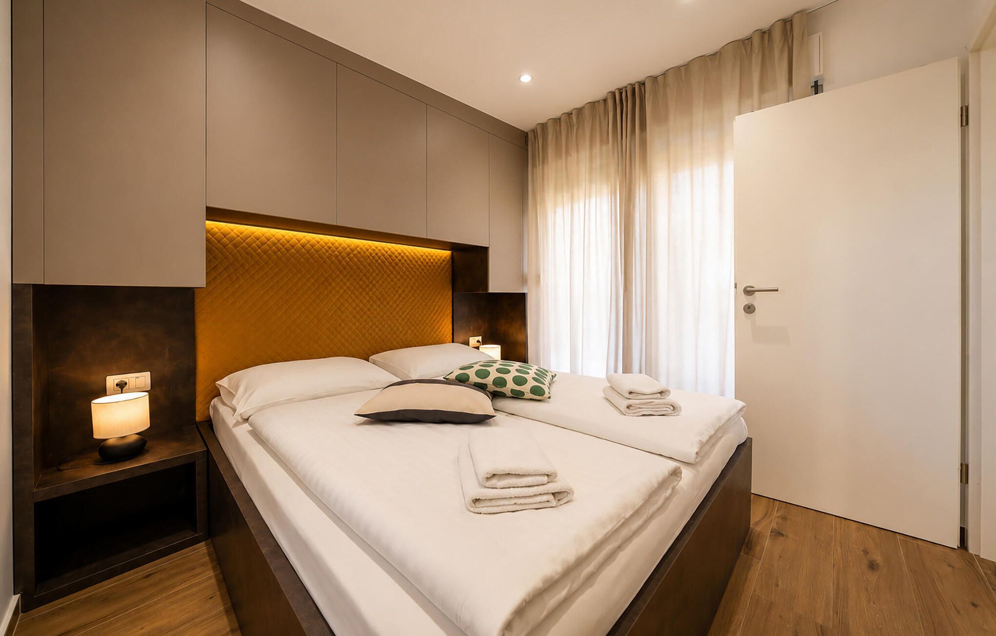 Une chambre d’hôtel avec un lit, une table de chevet, une lampe et une porte.