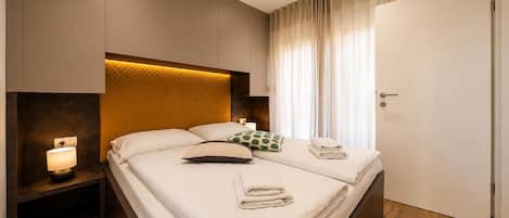 Ein Hotelzimmer mit Bett, Nachttisch, Lampe und Tür.