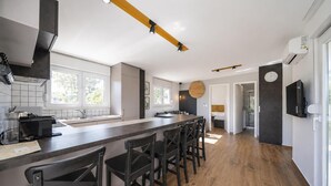 Eine moderne Küche mit einer langen Kochinsel, Barhocker, einem Einbauofen und einem großen Fenster.