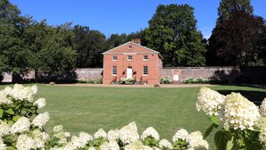 A red brick building with a symmetrical facade, a central entrance, and a well-maintained lawn in front. - The Garden Collection at Woodhall Park | Sleeps 12 | Wood Fired Hot Tub (Watton at Stone)