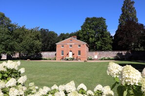 A red brick building with a symmetrical facade, a central entrance, and a well-maintained lawn in front. - The Garden Collection at Woodhall Park | Sleeps 12 | Wood Fired Hot Tub (Watton at Stone)