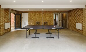 A ping pong table in a room with brick walls and a white door. - The Garden Collection at Woodhall Park | Sleeps 12 | Wood Fired Hot Tub (Watton at Stone)