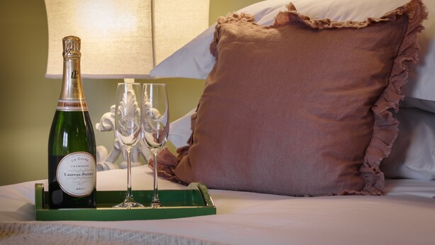 A bed with a green tray holding a bottle of champagne and two glasses. - The Garden Collection at Woodhall Park | Sleeps 12 | Wood Fired Hot Tub (Watton at Stone)
