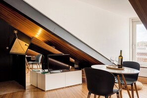 Ein modernes Schlafzimmer im Loft-Stil mit schrägem Dach, integriertem Schreibtisch und Essbereich mit Tisch und Stühlen.