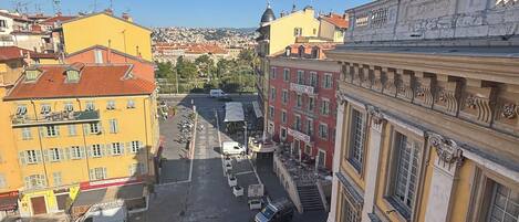 A street view with buildings, a clock tower, and parked vehicles.