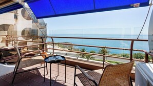 A balcony with wicker chairs, a small table, and a view of the sea. - Varandas do Mar - Estoril Atlantic Views (Cascais)