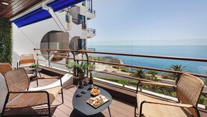 A balcony with wicker furniture, a table with snacks and drinks, and a view of the ocean. - Varandas do Mar - Estoril Atlantic Views (Cascais)