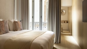 Ett hotellrum med en säng, gardiner, utsikt över omgivningarna och ett litet pentry.