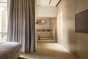 A hotel room with a bed, a bathroom with a mirror and a sink, and a view of the outside. - Luxurious suite - AC- 2P- Madeleine/Saint Honore (Paris)