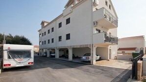 Un edificio de varios pisos con un estacionamiento, un autobús y un coche estacionados al frente.
