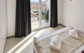 Ein Hotelzimmer mit einem Bett, zwei Handtüchern, einem Fenster mit Vorhängen und Blick auf Gebäude sowie ein Auto draußen.