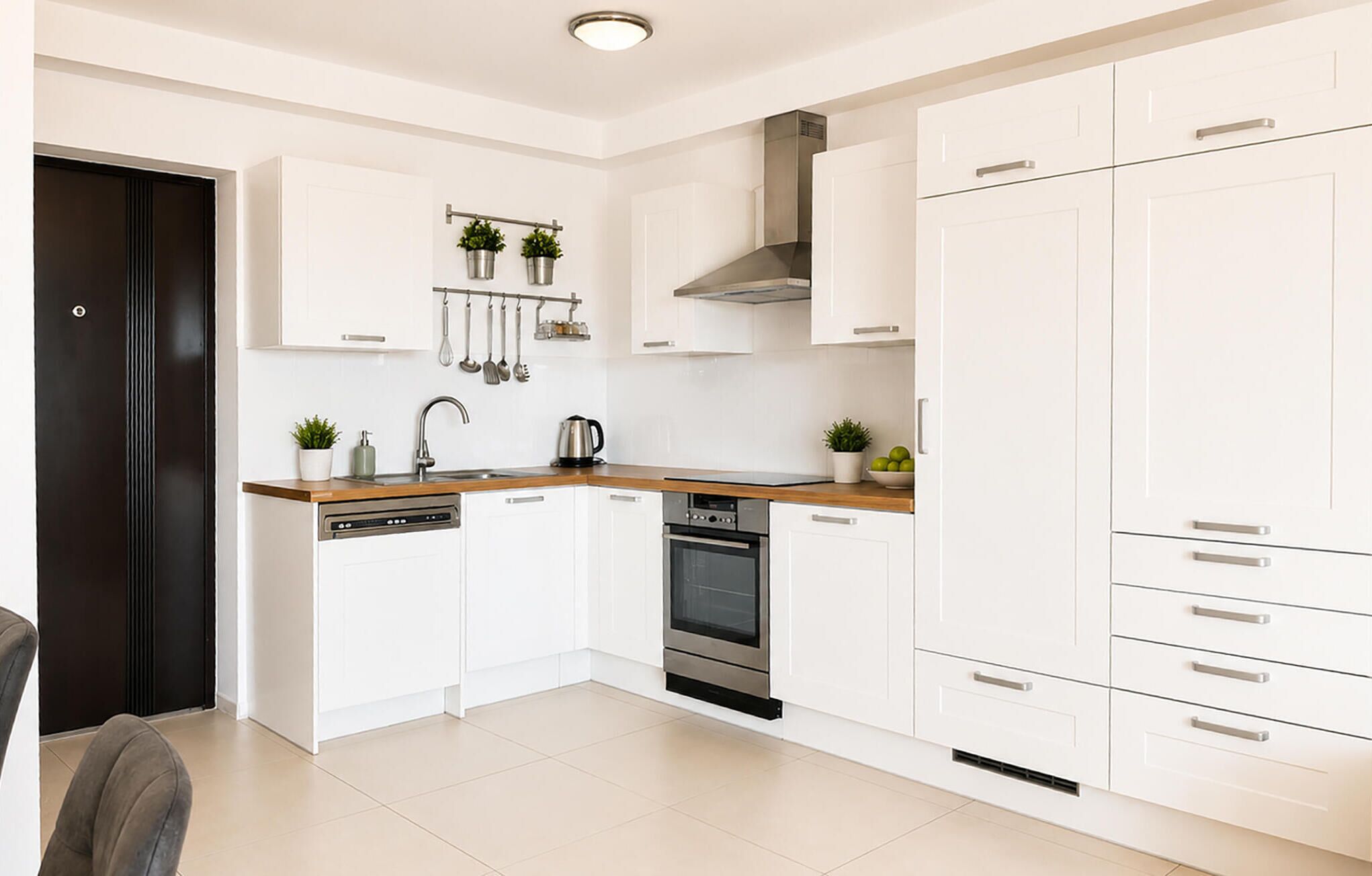 A modern kitchen with white cabinets, a stainless steel oven, and a wooden countertop.