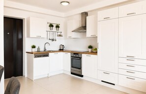 Een moderne keuken met witte kasten, een roestvrijstalen oven en een houten aanrecht.