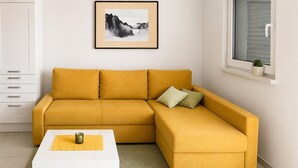 Un sofá seccional amarillo con una mesa de centro blanca y un cuadro en la pared.