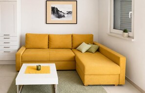 Ein gelbes, modulares Sofa, ein weißer Couchtisch und ein gerahmtes Bild an der Wand.