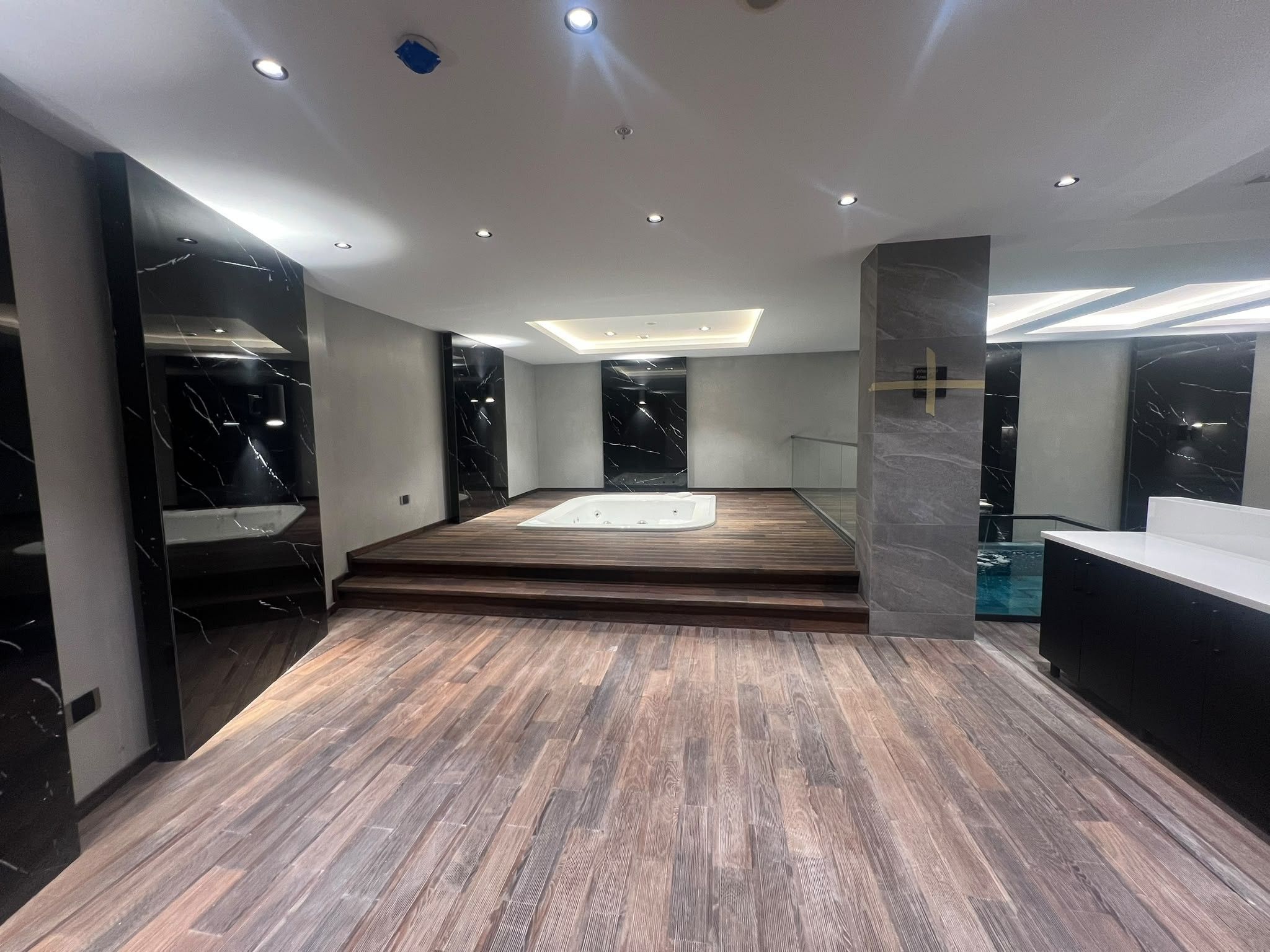 Un baño moderno con suelo de madera, una bañera y paredes de mármol.