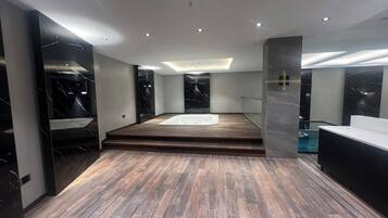 Un baño moderno con suelo de madera, una bañera y paredes de mármol.