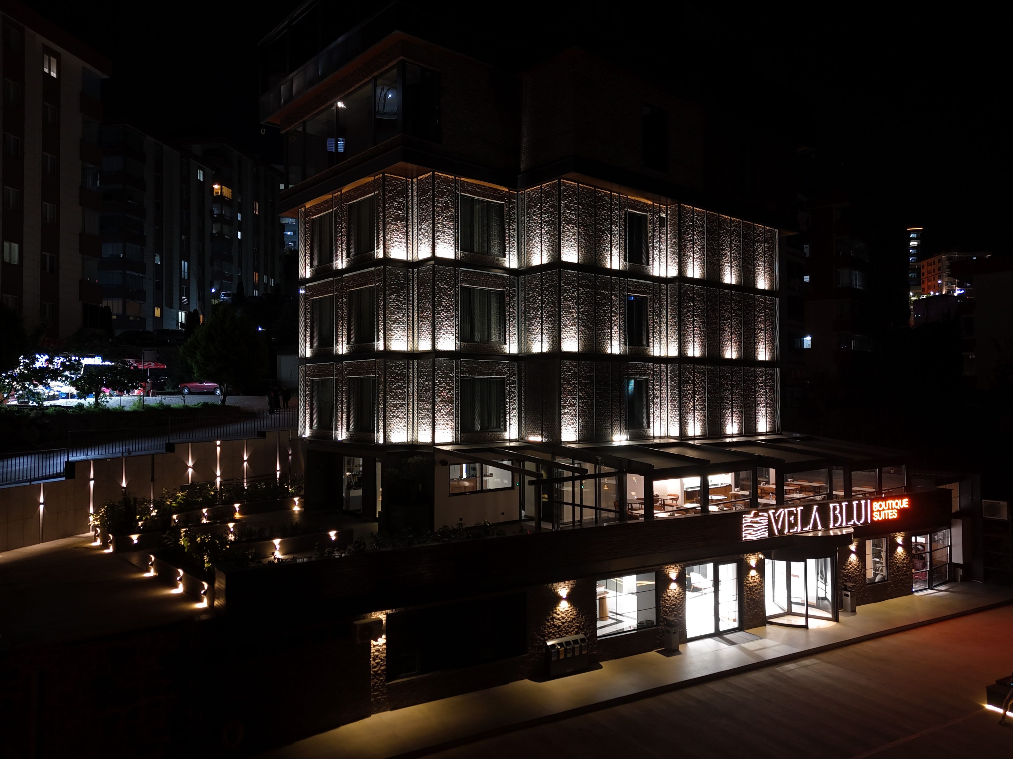 Un edificio moderno con un cartel llamativo para 'VELA BLU SUITES' de noche.