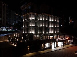 Um edifício moderno com uma placa chamativa para 'VELA BLU SUITES' à noite.