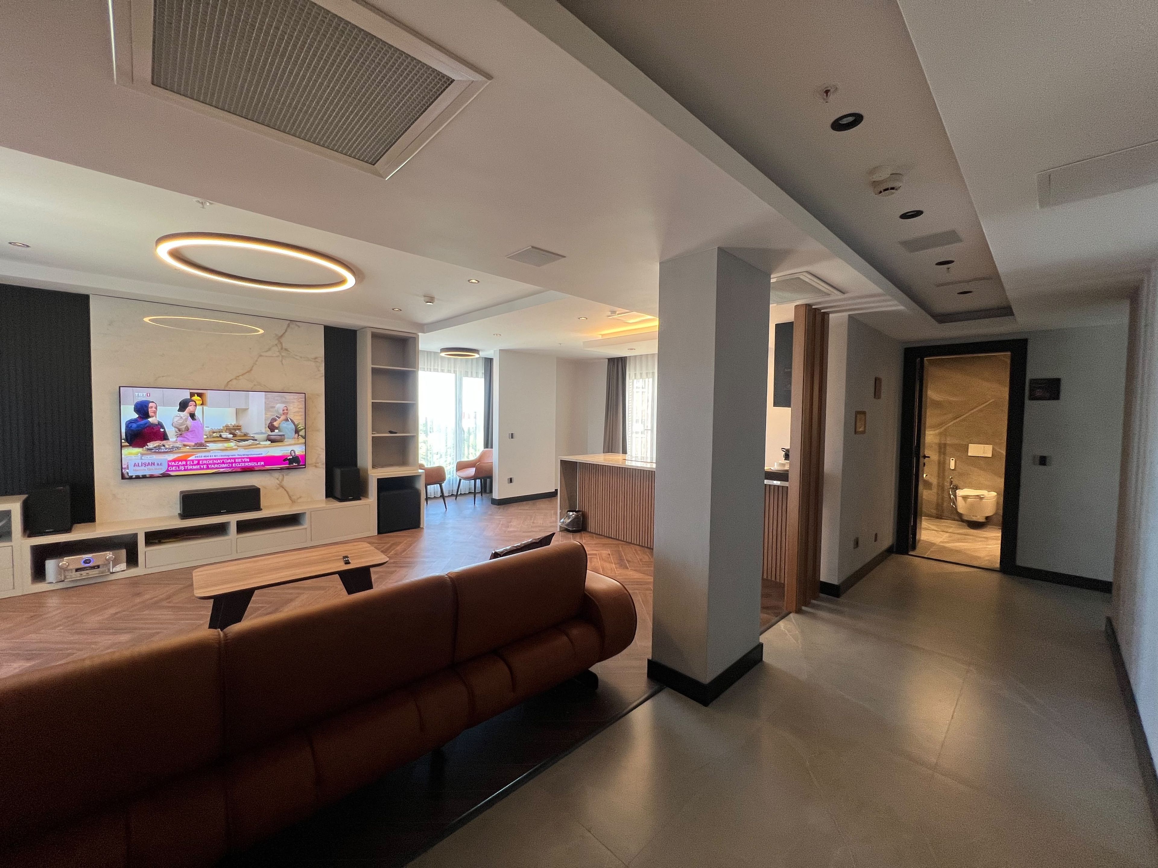 Un moderno vestíbulo de hotel con zona de estar, televisor de pantalla plana y mostrador de recepción.