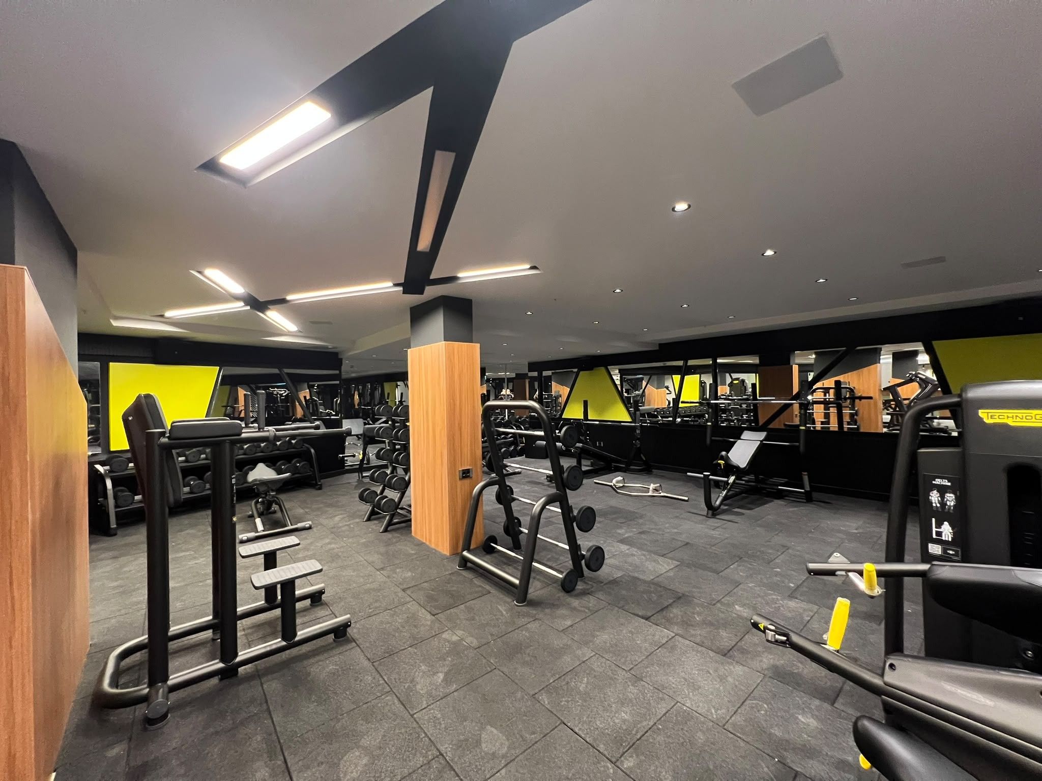 A gym with various exercise equipment, including dumbbells, weight machines, and a treadmill.