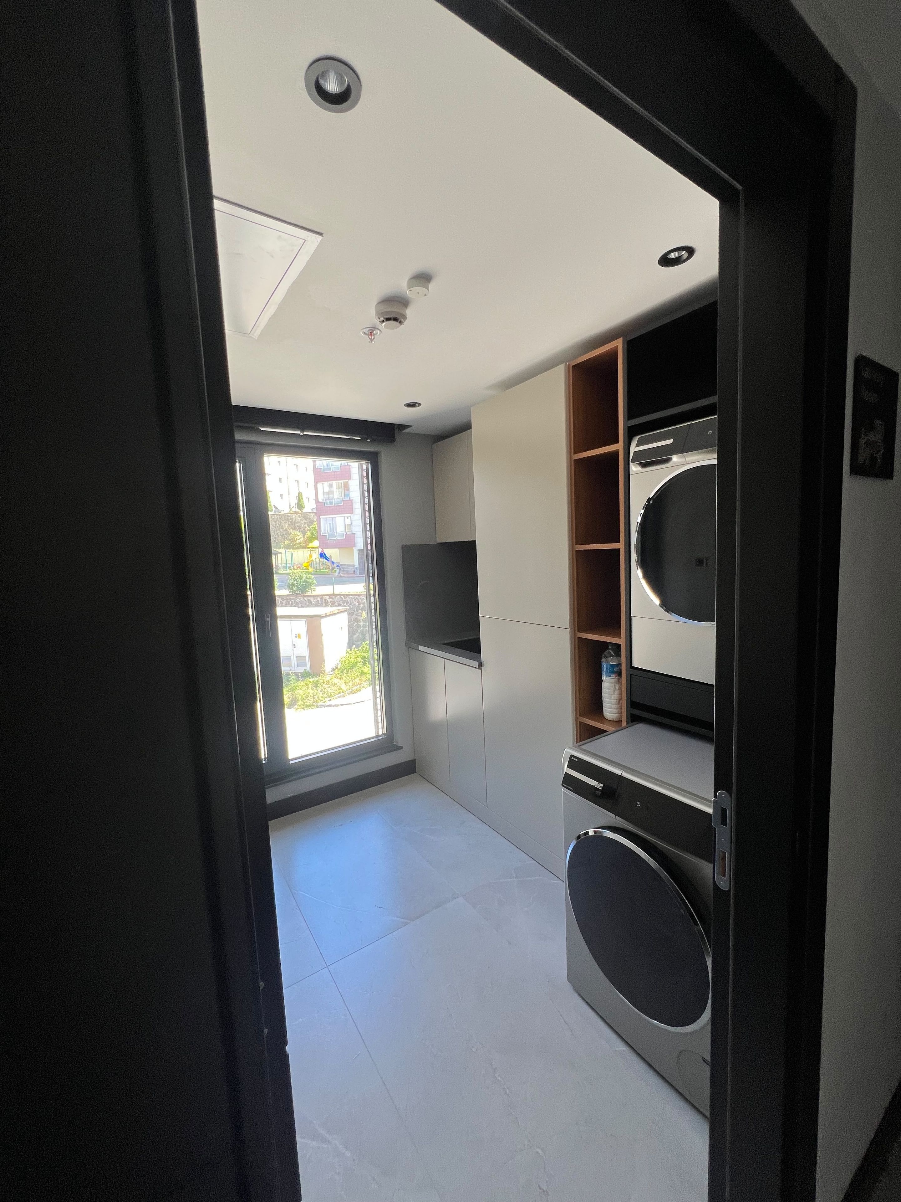 A modern kitchen with built-in appliances, a large window, and a view of the outside.