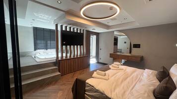 Une chambre d’hôtel moderne équipée d’un grand lit, d’une télévision, d’un miroir et d’une salle de bain avec baignoire.