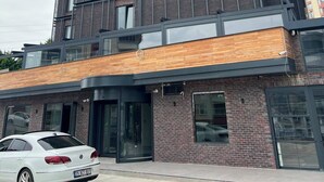 Un immeuble à plusieurs étages doté d’une architecture moderne, caractérisé par un mélange de façades en brique et en verre, et surmonté d’un toit plat avec une antenne parabolique.