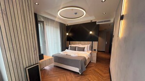 Une chambre d’hôtel moderne dotée d’un grand lit, d’un plancher en bois et d’un plafond avec des spots encastrés.
