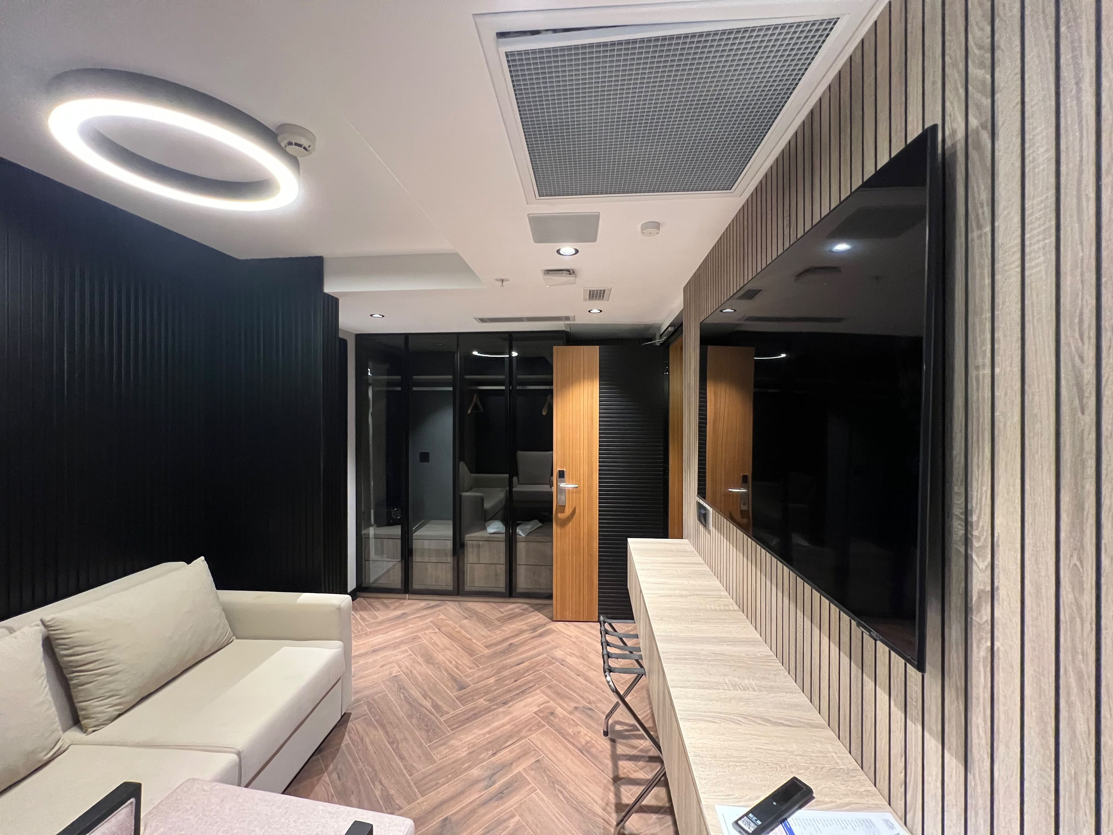 A modern interior with a sofa, a wooden bench, and a large mirror.