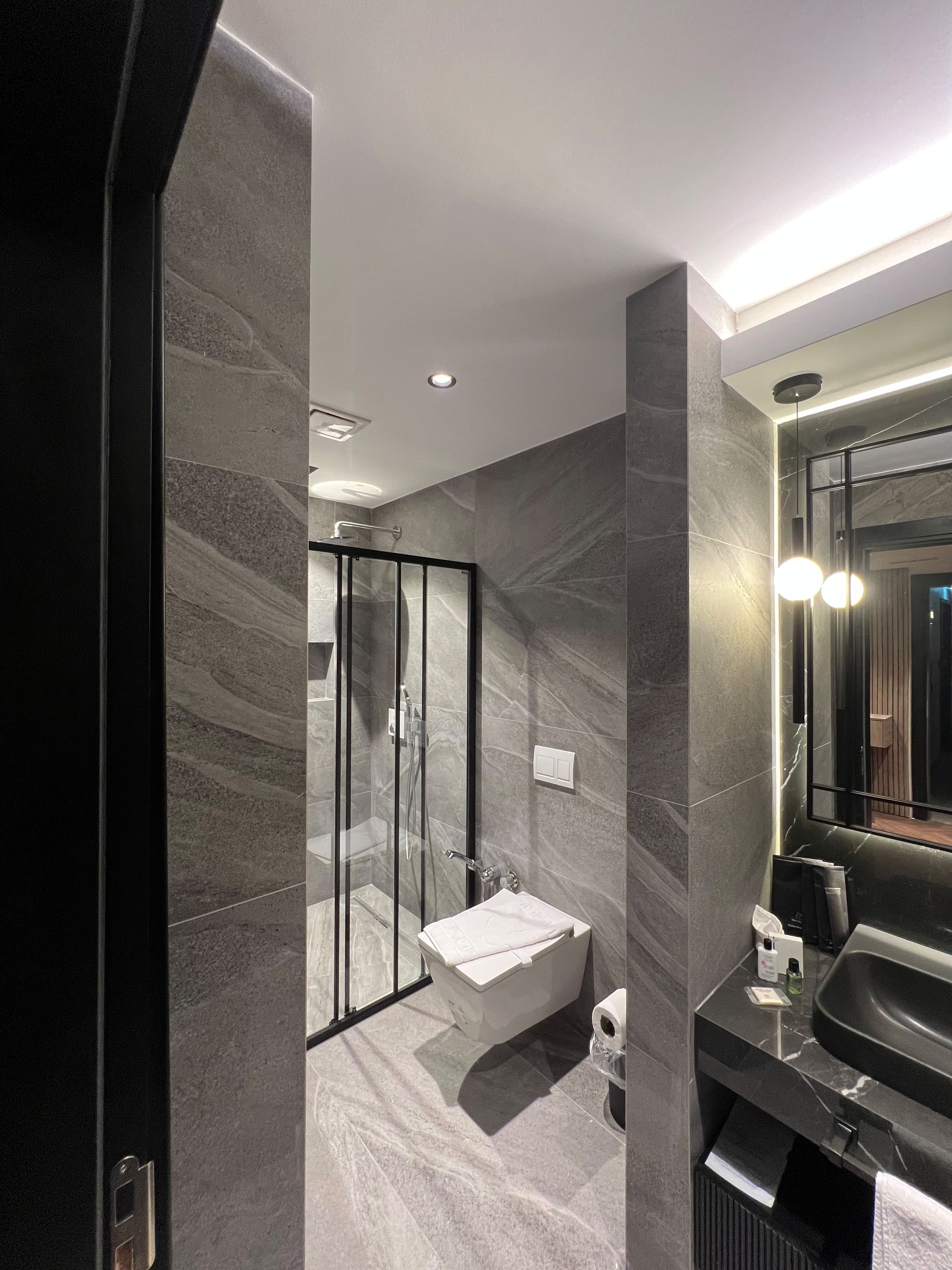 A modern bathroom with a glass-enclosed shower, a white sink, and a large mirror.