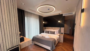 Une chambre d’hôtel moderne avec un grand lit, des tables de chevet, un téléviseur intégré et un plancher en bois.