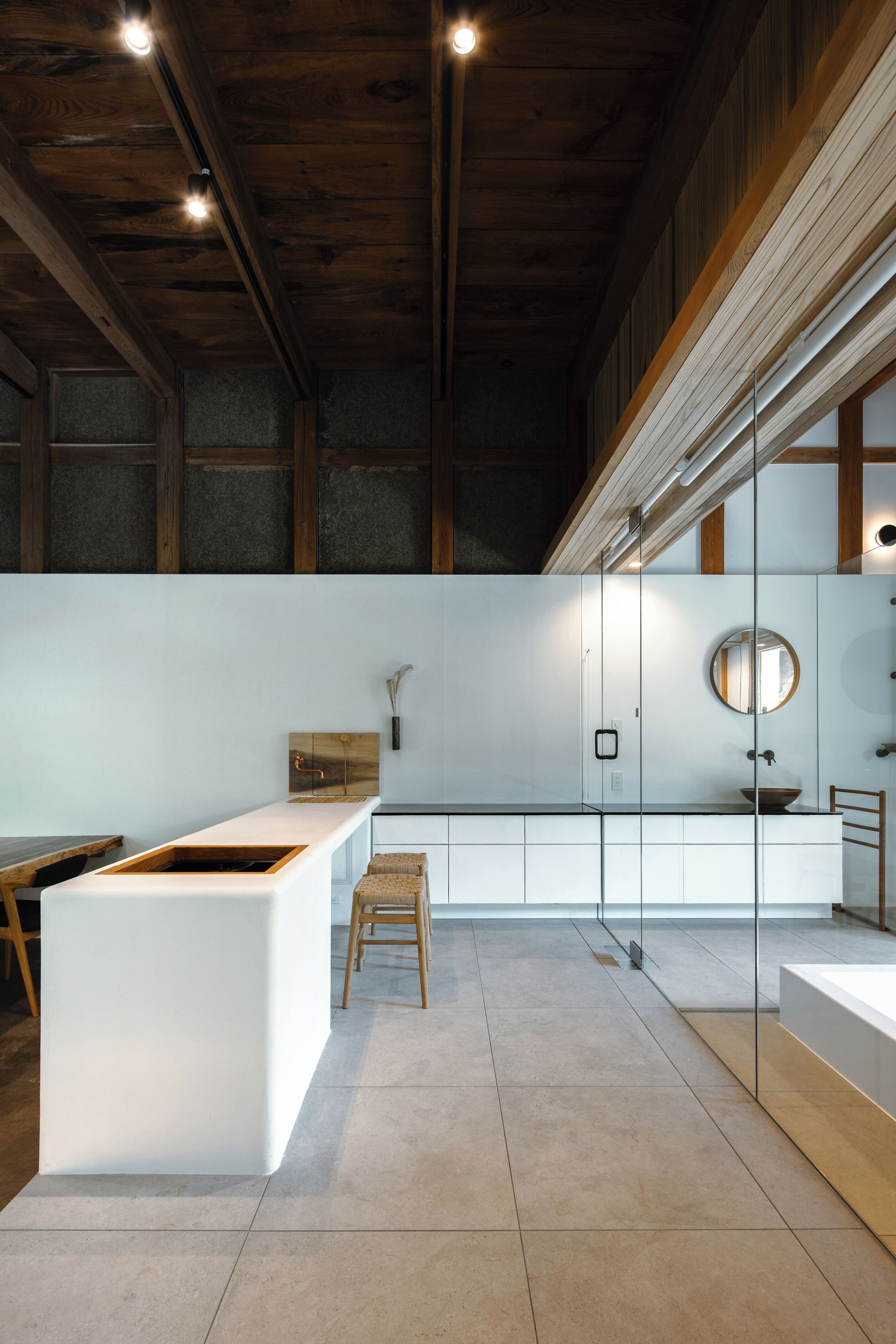 A modern kitchen with a central island, wooden beams on the ceiling, and a large window.