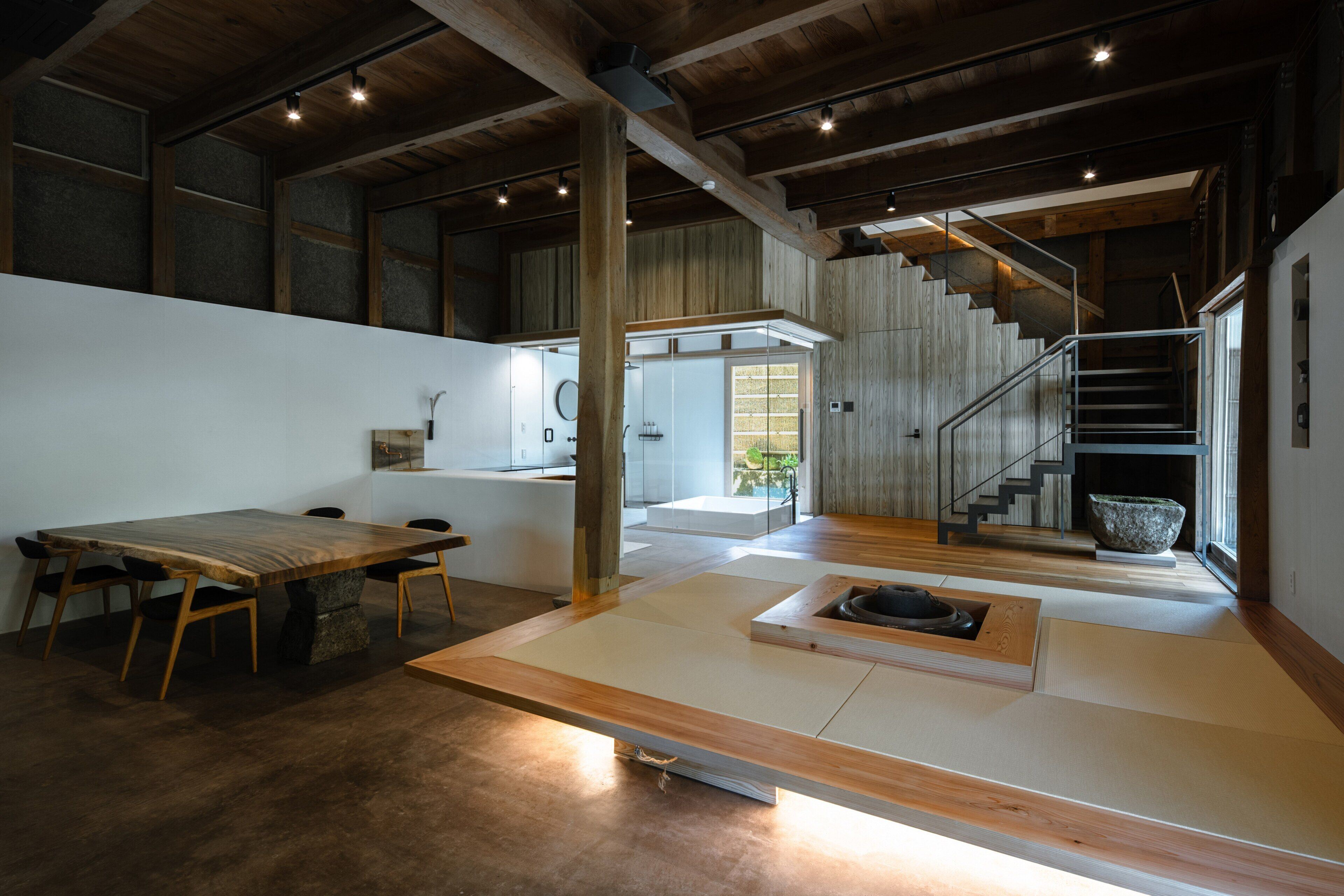 A spacious interior with a wooden dining table, a staircase, and a view of the outdoors.