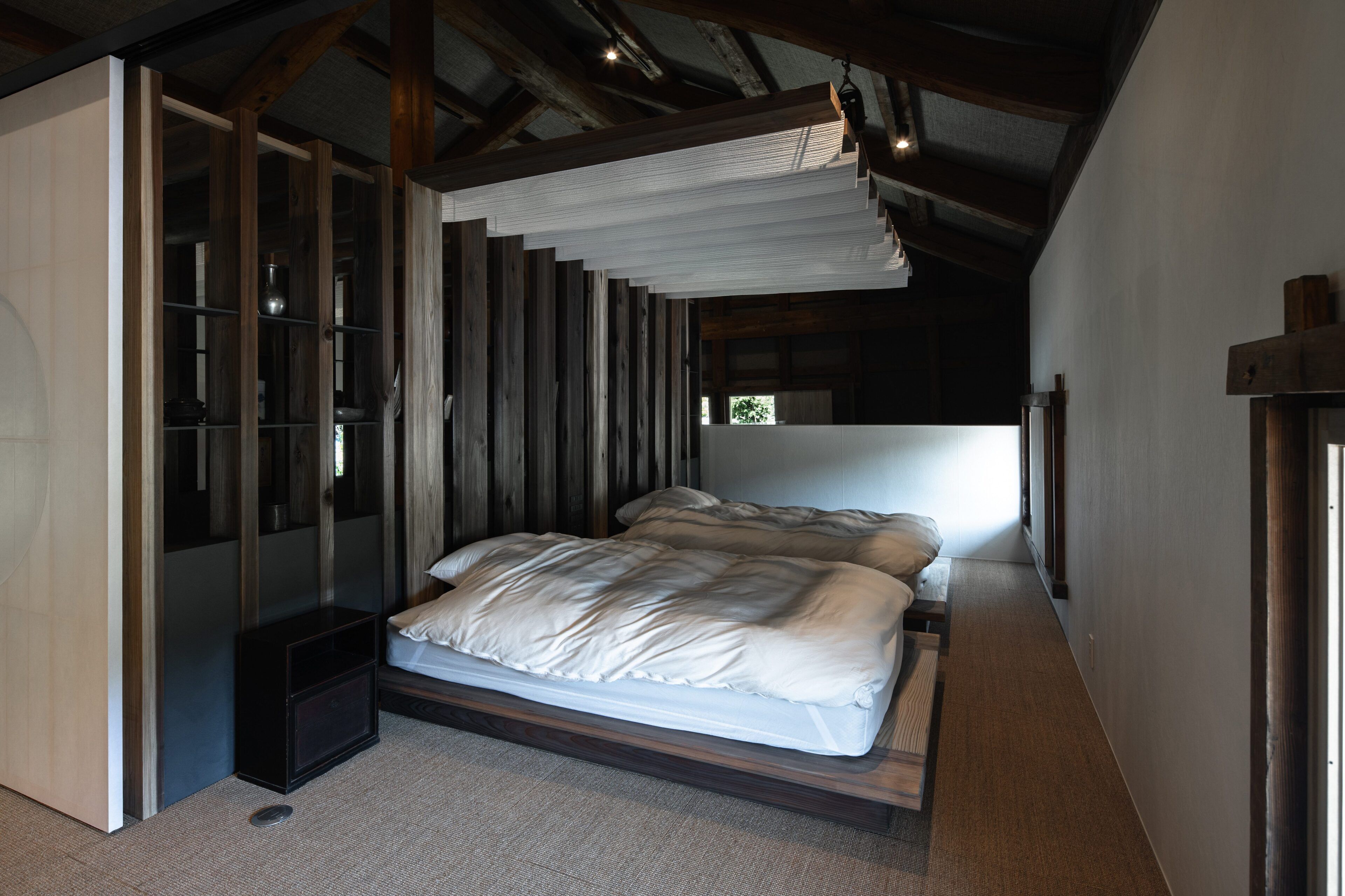 A bedroom with a large bed, a built-in wardrobe, and a sloped ceiling.