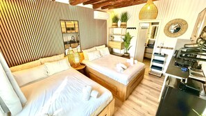 A modern hotel room with a large bed, a small desk, a mirror, and a kitchen area. - Naousaki Premium Studios 2 - Heart of Naousa, Paros (Naousa)