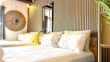 A bed with white linens, a round wall mirror, and a wooden slat wall.