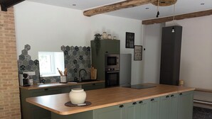 A modern kitchen with a central island, built-in appliances, and a herringbone floor pattern. - Fully renovated country house (Barville)