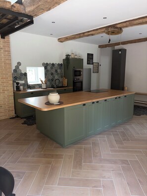 A modern kitchen with a central island, built-in appliances, and a herringbone floor pattern. - Fully renovated country house (Barville)