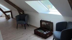 A room with a sloped ceiling, wooden beams, a skylight, and two chairs. - Fully renovated country house (Barville)