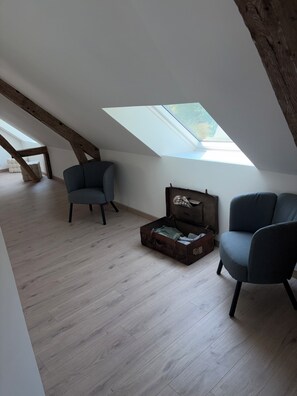 A room with a sloped ceiling, wooden beams, a skylight, and two chairs. - Fully renovated country house (Barville)