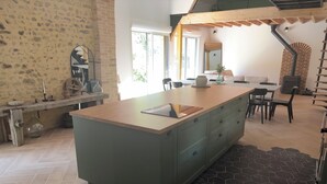 A kitchen with a central island, a dining area with chairs, and a staircase. - Fully renovated country house (Barville)