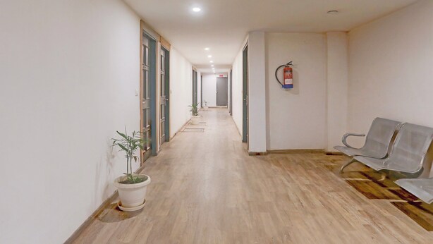 A hallway with a potted plant, a fire extinguisher, and a bench. - Townhouse Prayagraj Near Railway Station Formerly Santosh Palace (Prayagraj)